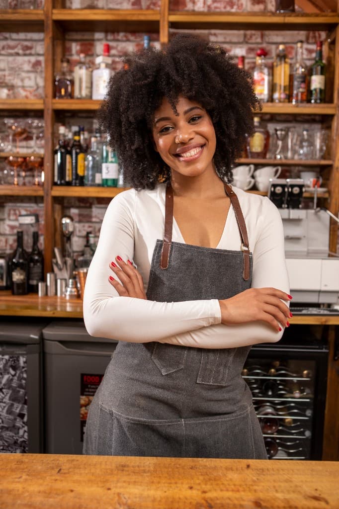 A smiling barista behind the counter at a specialty coffee shop